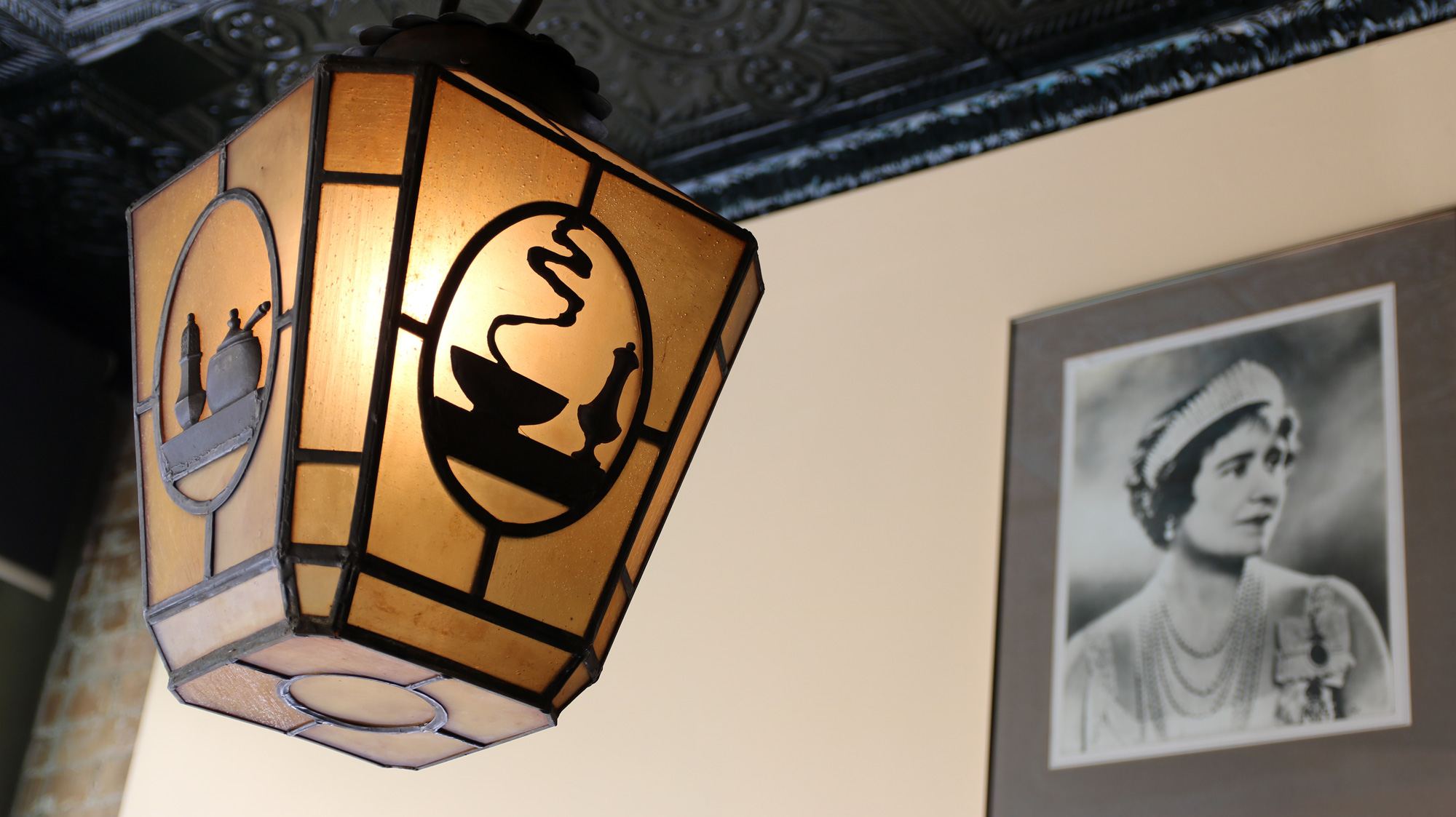 Antique café light hanging in front of one of the original photos of the Queen Mother that gave the restaurant its name